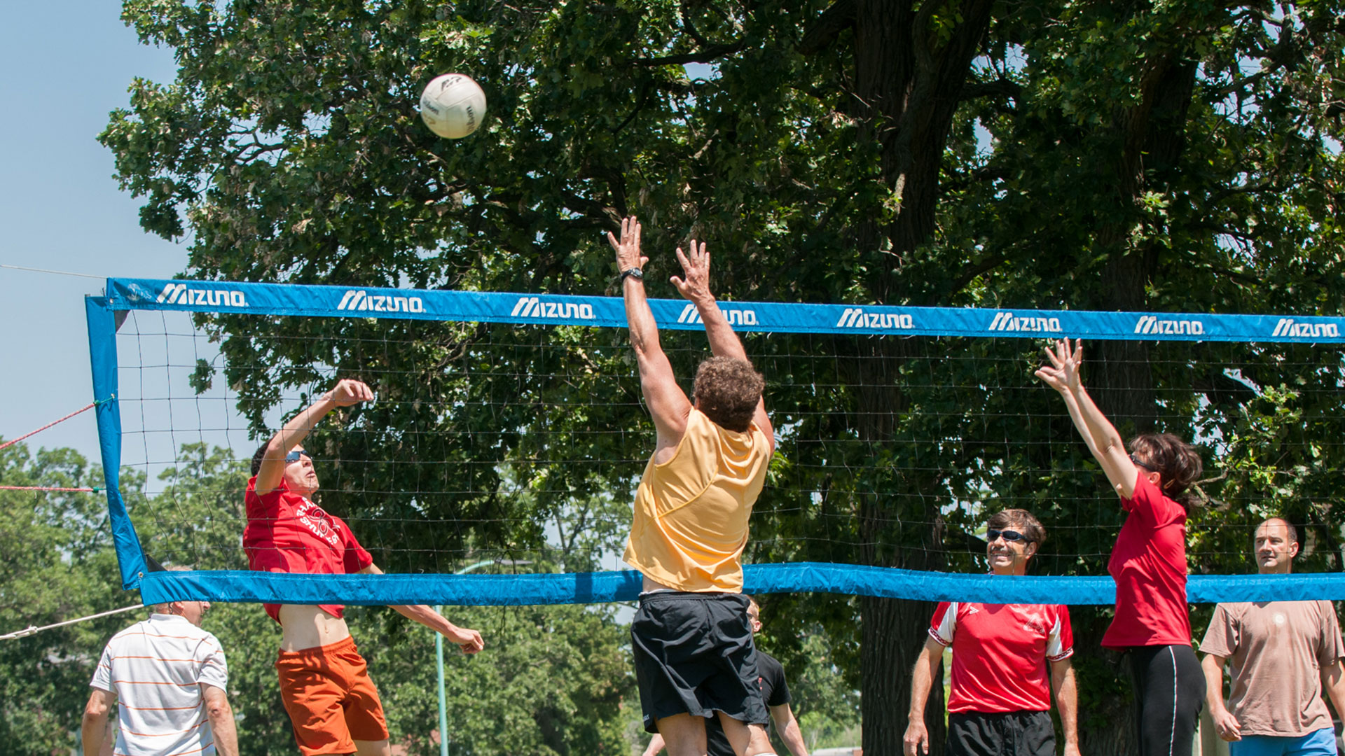 Group of people playing vollyeball outdoors.