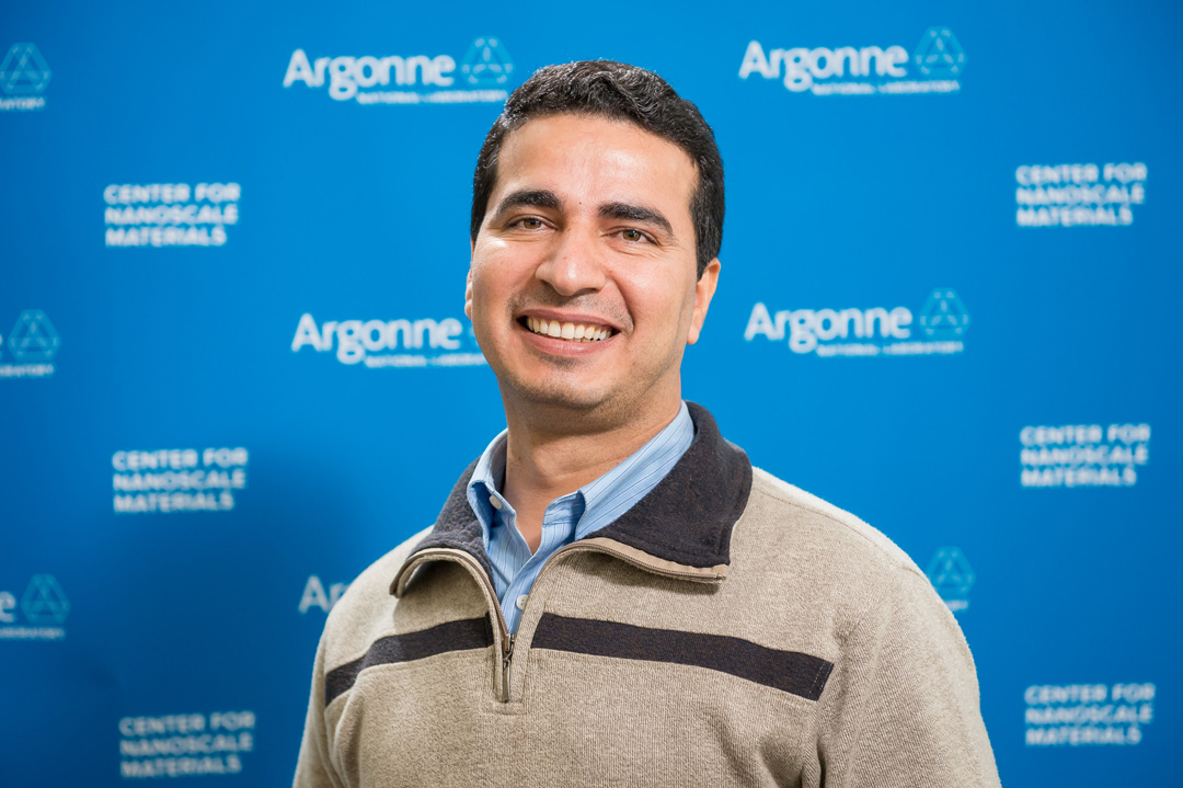 Smiling man in front of Blue Argonne logo backdrop.