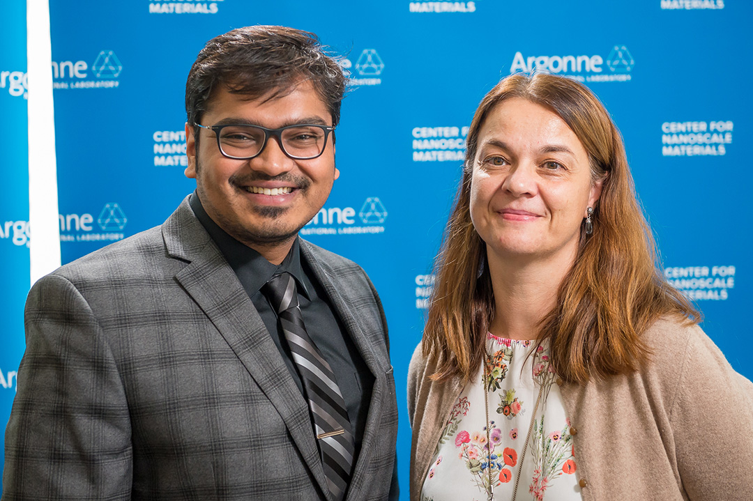 Man wearing glasses and woman, in front of Blue Argonne logo backdrop.