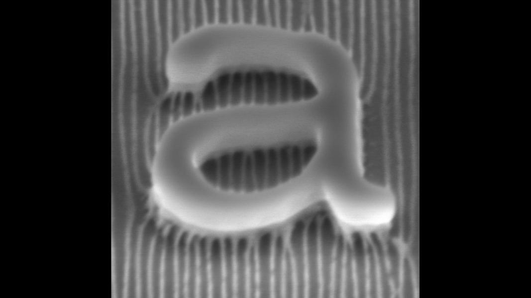 Grayscale image of raised letter "a" over uneven striped background.
